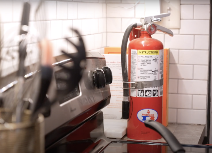 Image of a fire extinguisher next to a stove top in a kitchen