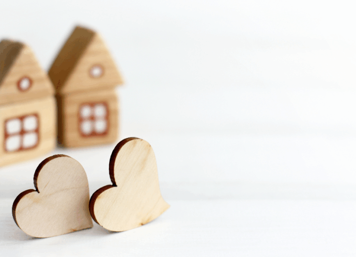 Two decorative wooden hearts in front of two wooden decorative homes