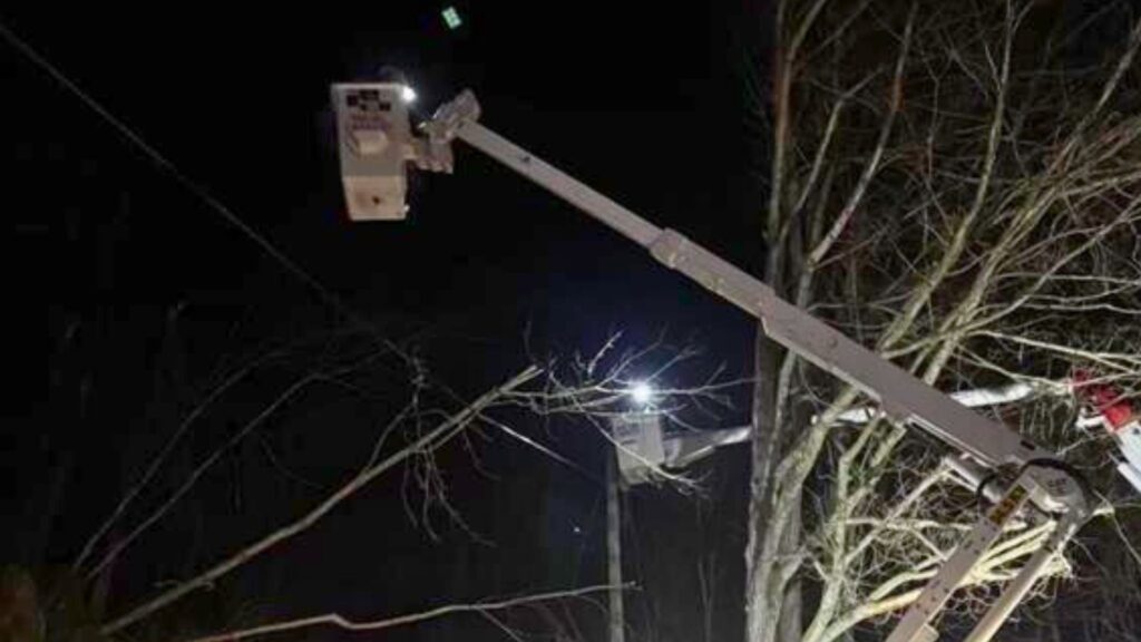 A photo of two lineworkers in bucket trucks restoring power at night.